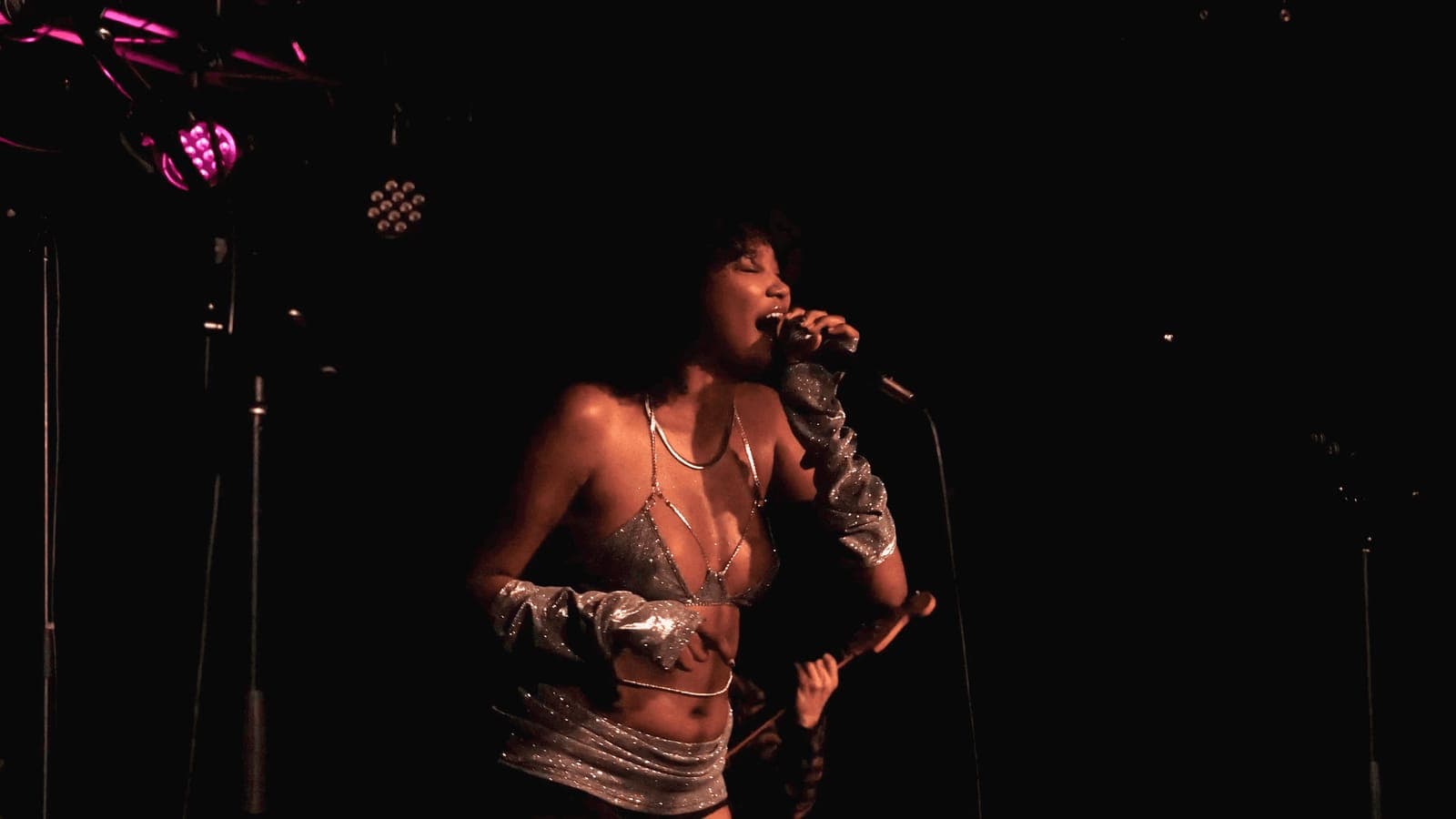 A singer performs under purple light on a dark stage
