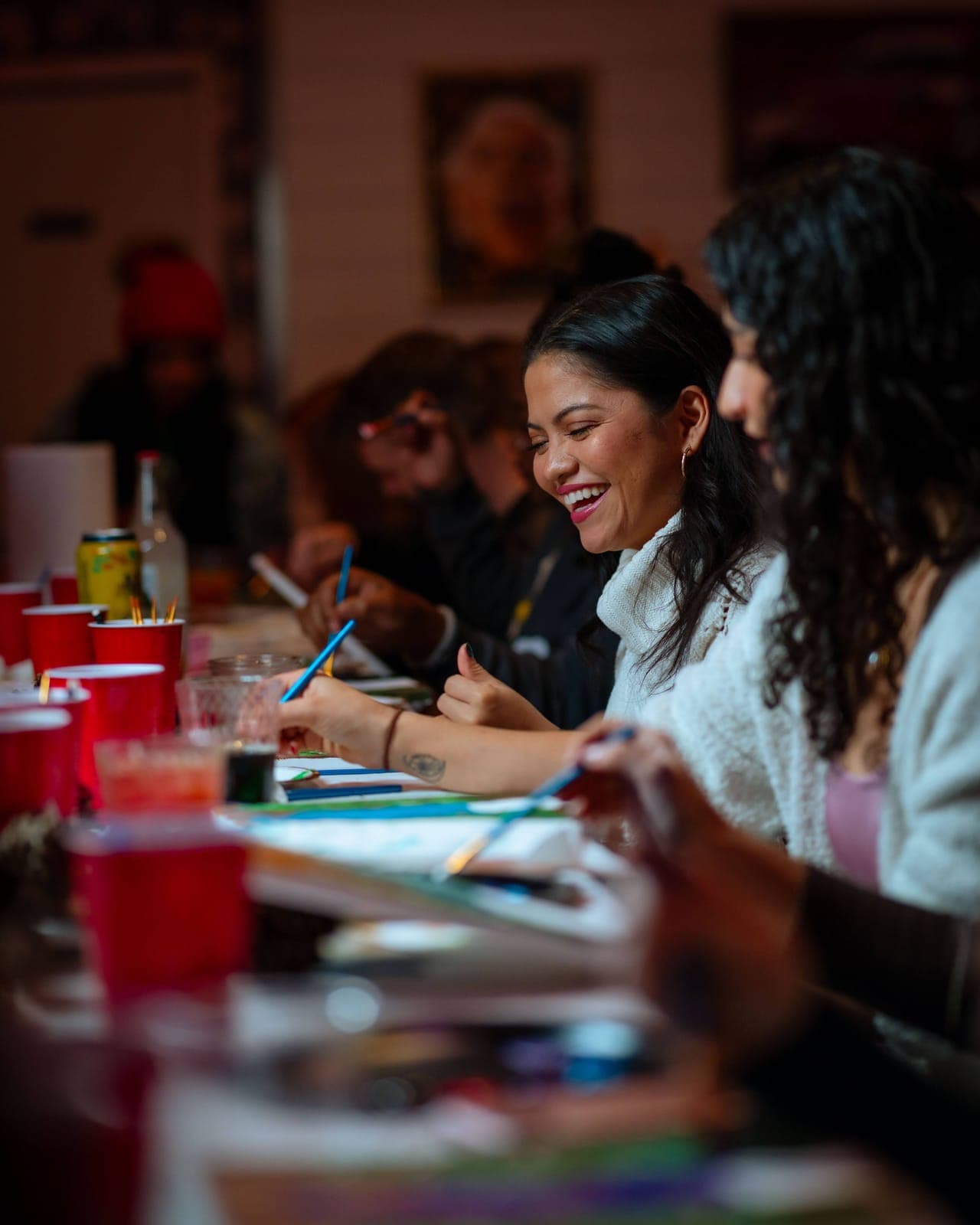 People paint together at a long table at a creative night