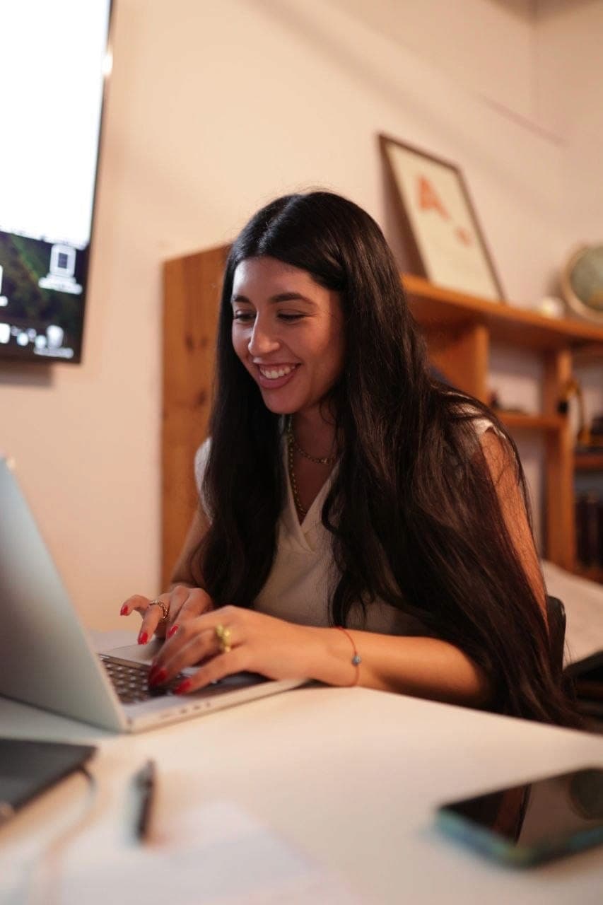 A woman smiles while working at a laptop
