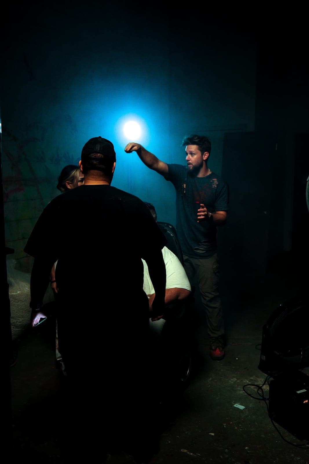 People gather under a single blue light at a night show