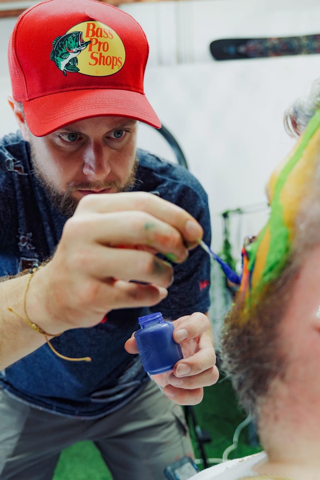 An artist in a red cap paints bright green colour onto a guest at a Fitfo Labs night