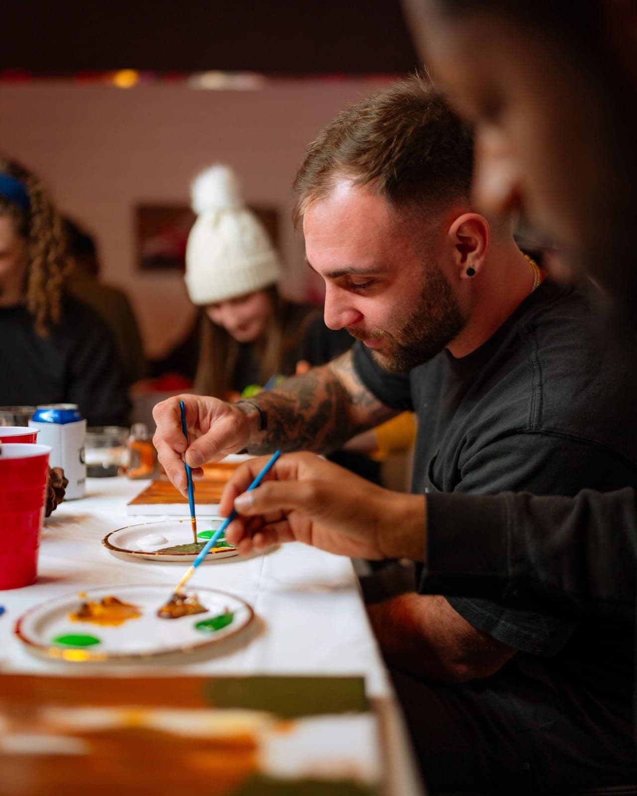 A man paints at a long table during a creative night