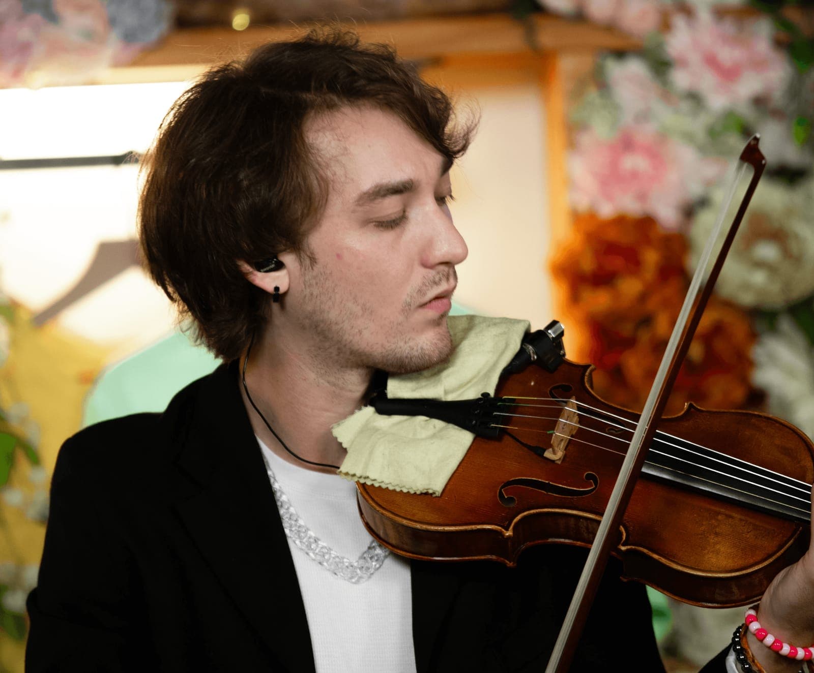 A violinist plays in front of flowers