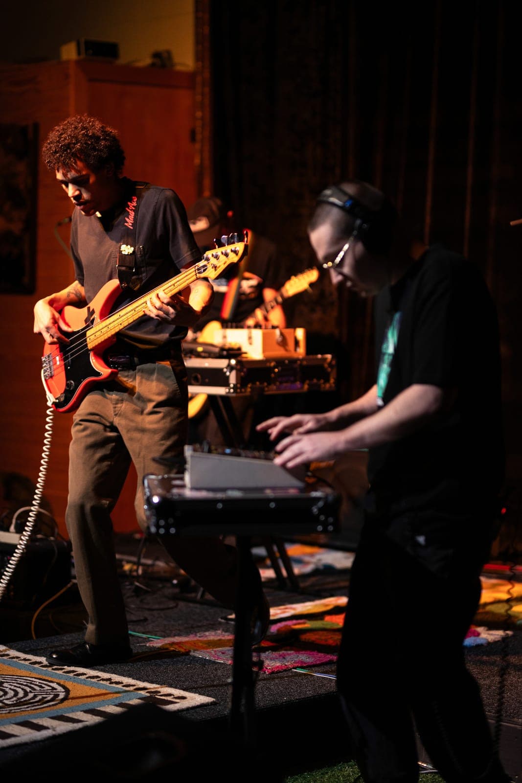 A guitarist and a keyboard player perform together under warm light