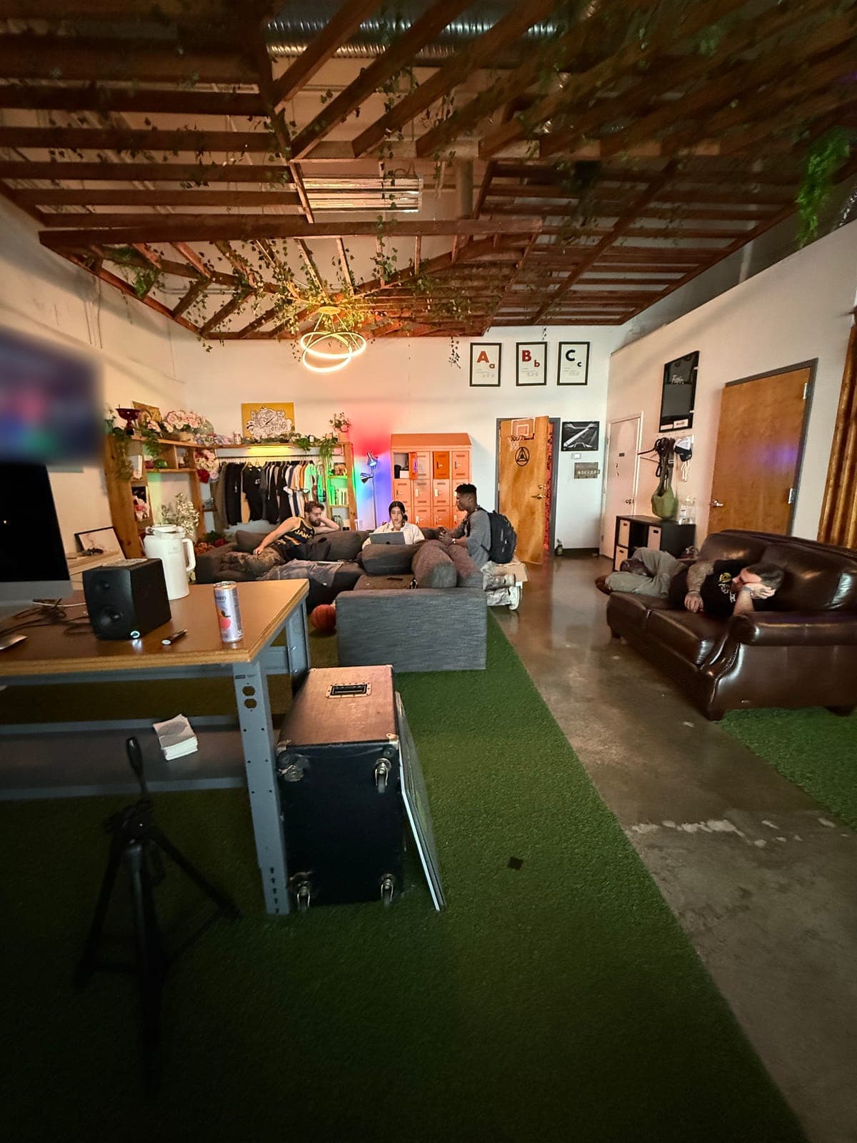 The Fitfo Labs lounge in Atlanta: vines over the beams, a ring light, orange lockers and friends on the couches